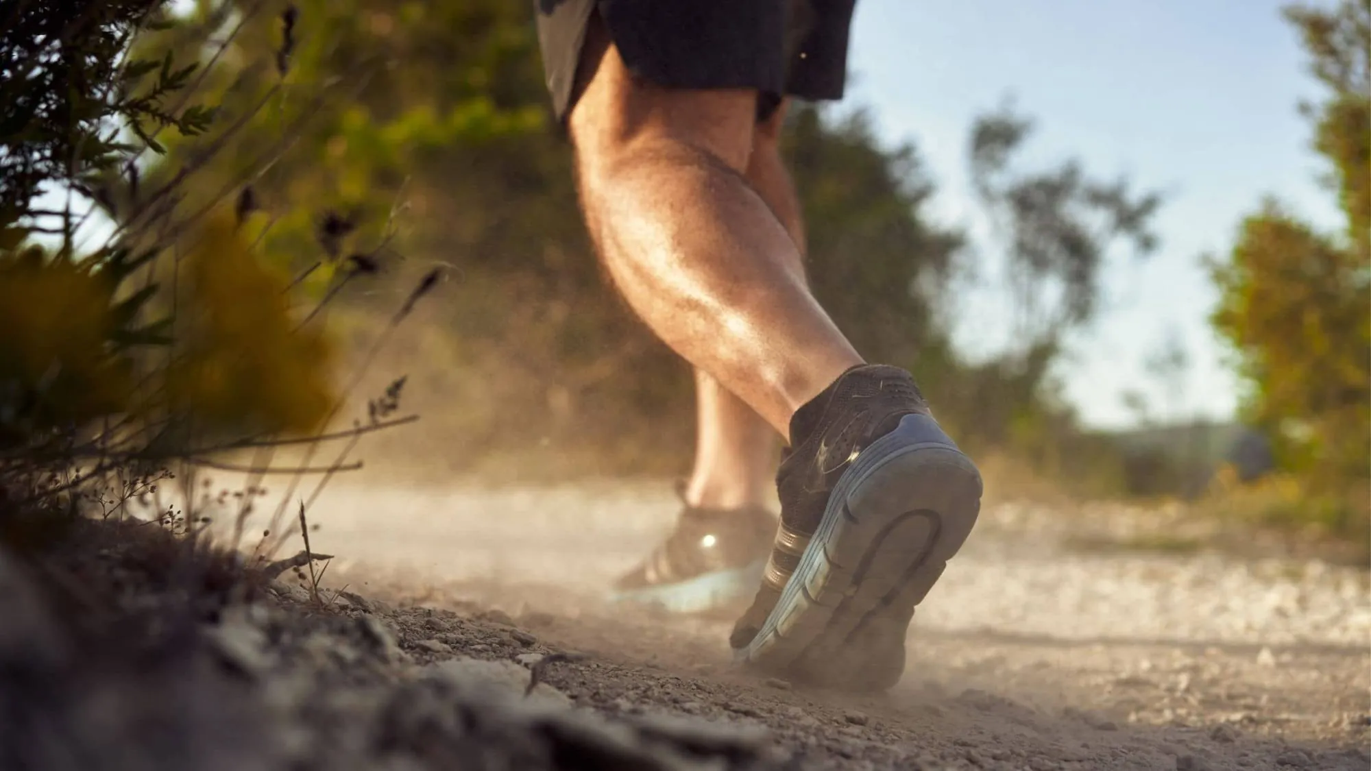 Close-up of a runner's heel and calf on a dusty trail